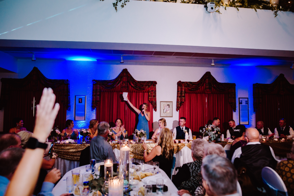 Maid of honor gives speech at wedding reception with bride and groom