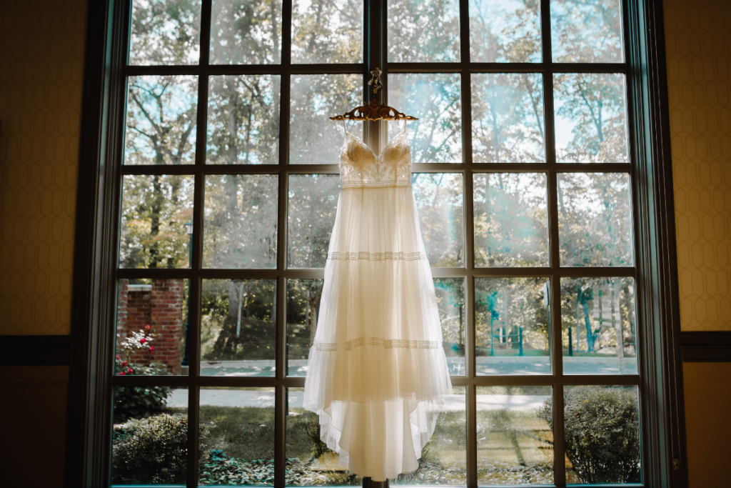 Wedding dress hanging in window in bridal suite