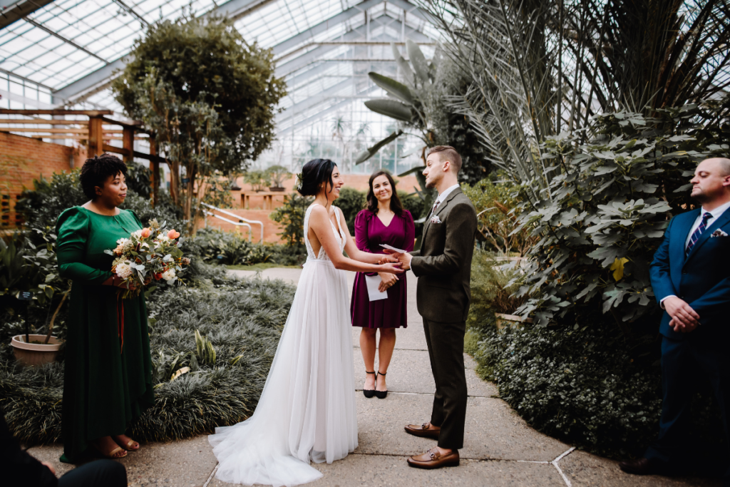 Bride and groom share vows at ceremony in a greenhouse